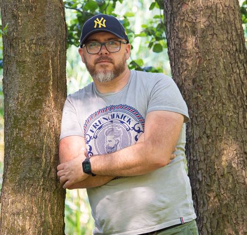 Krzysztof Kupren stoi przy drzewach