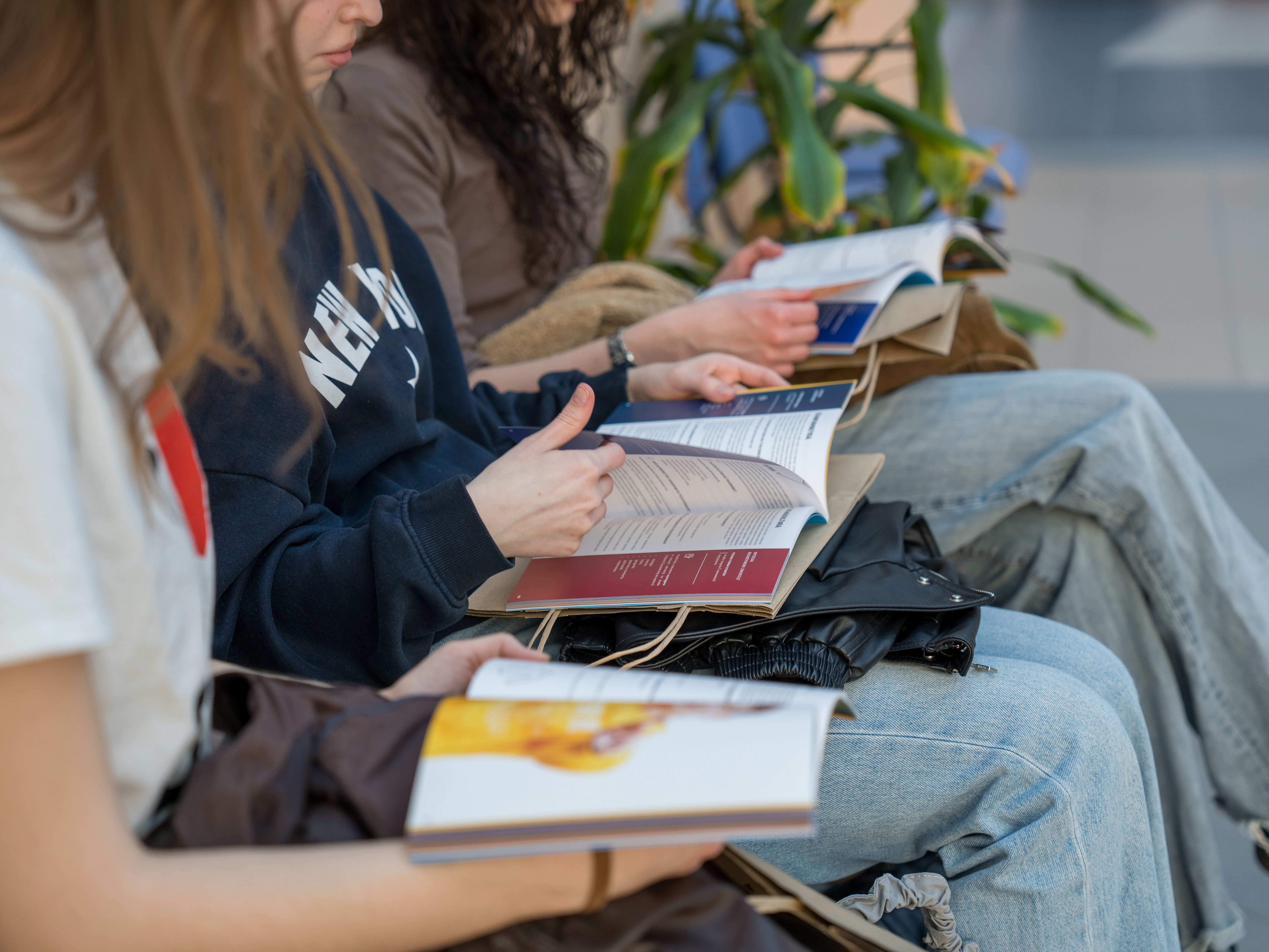 "Uczniowie siedzą obok siebie i przeglądają informatory"