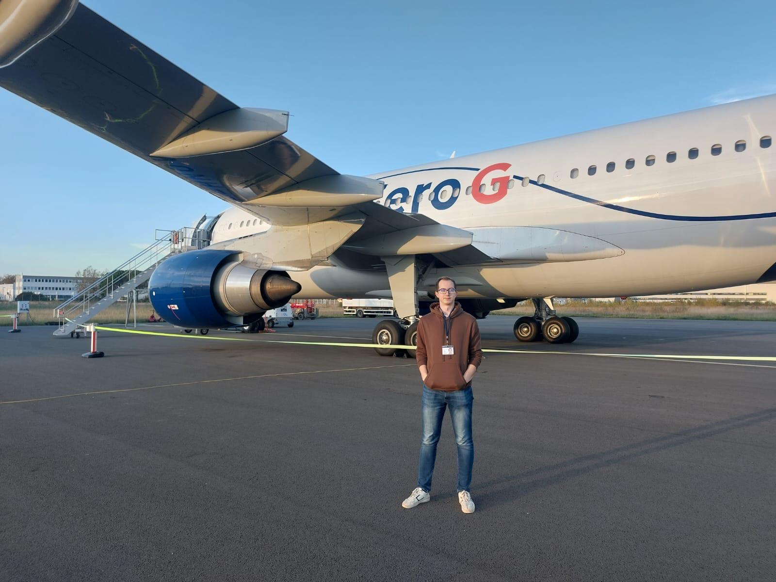 Doktorant z UWM pozuje przed samolotem, który bierze udział w lotach parabolicznych