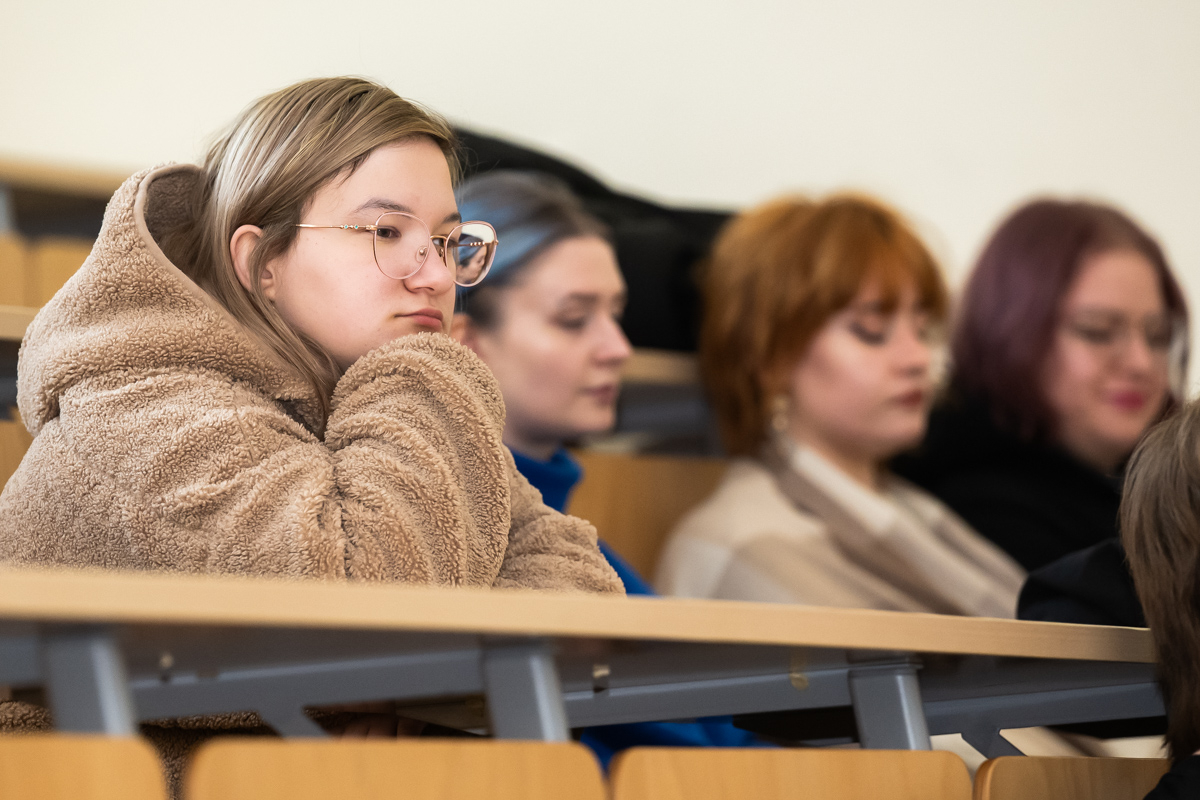 studenci siedzą w ławkach i słuchają wykładu