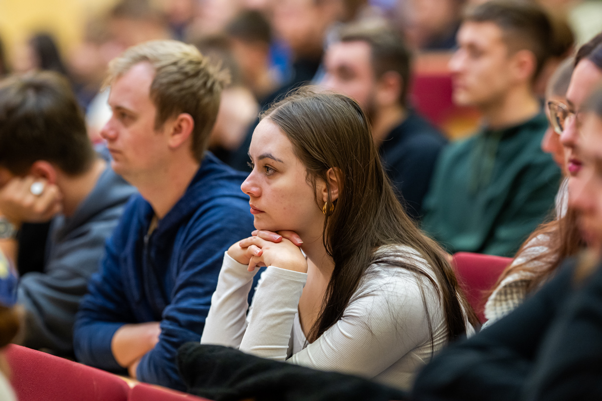 studenci siedzą w ławkach i słuchają wykładu