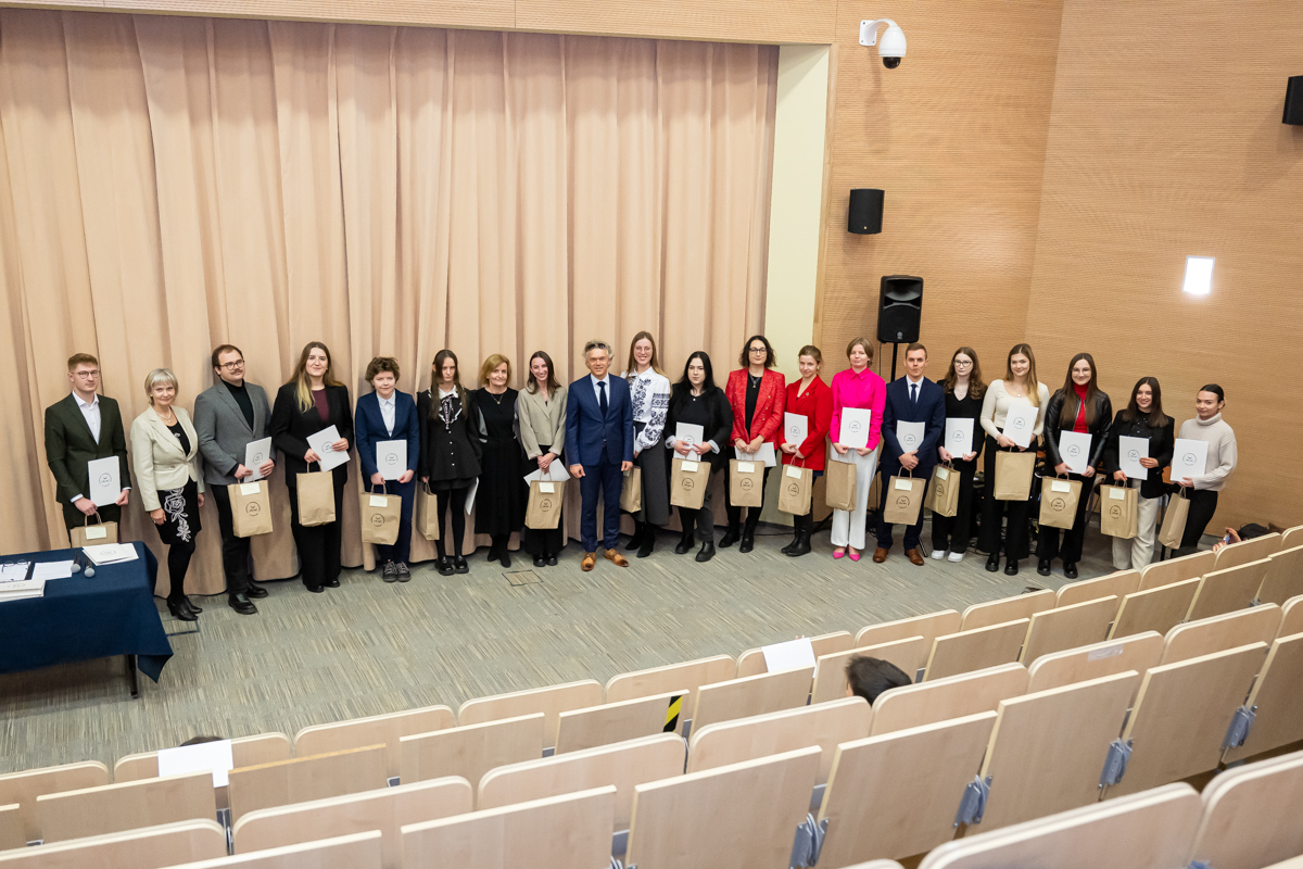 Absolwenci Wydziału Humanistycznego pozują z dyplomami w auli teatralnej