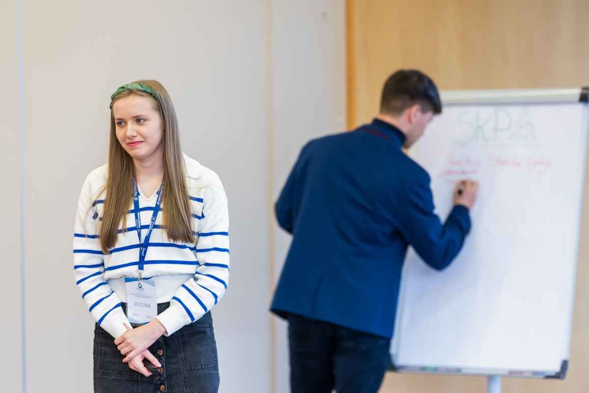 student pisze na tablicy, studentka stoi i referuje