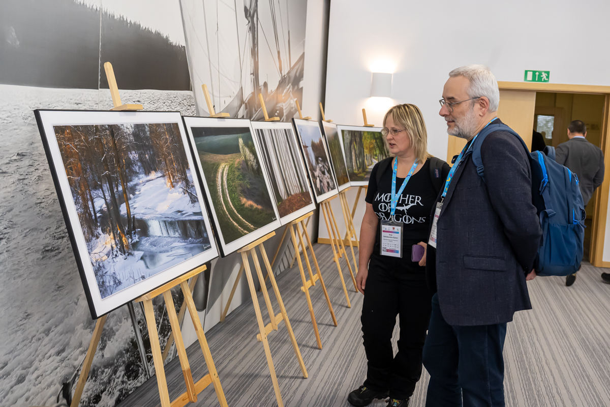 uczestnicy konferencji oglądają wystawę fotografii