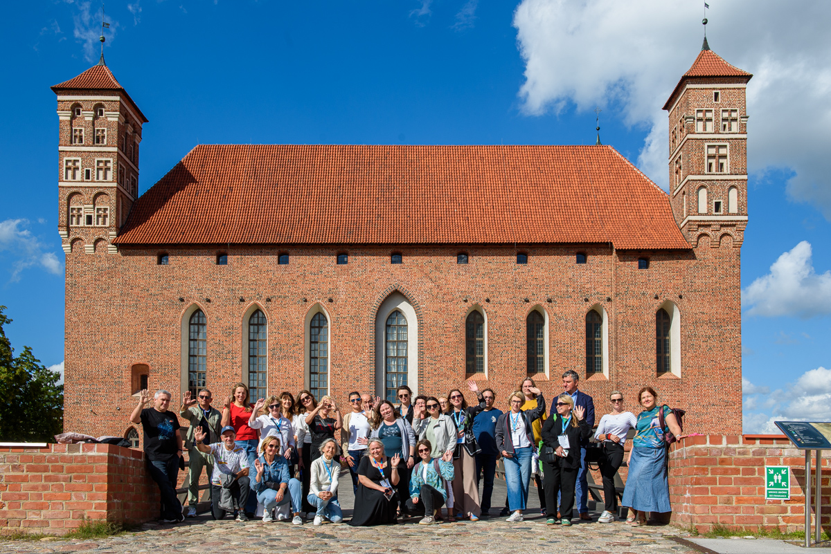XXXII Konferencja Redaktorów Czasopism Akademickich i Portali Uczelnianych w Olsztynie: zdjęcie grupowe uczestników przed zamkiem w Lidzbarku Warmińskim