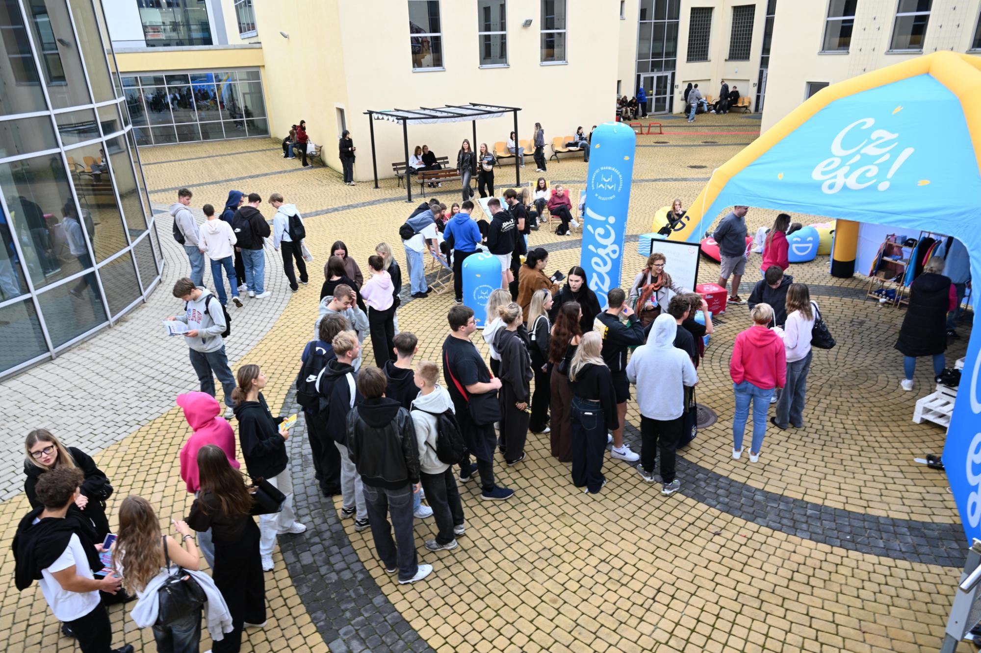 Kolejka ludzi czekających przed namiotem UWM z napisem Cześć