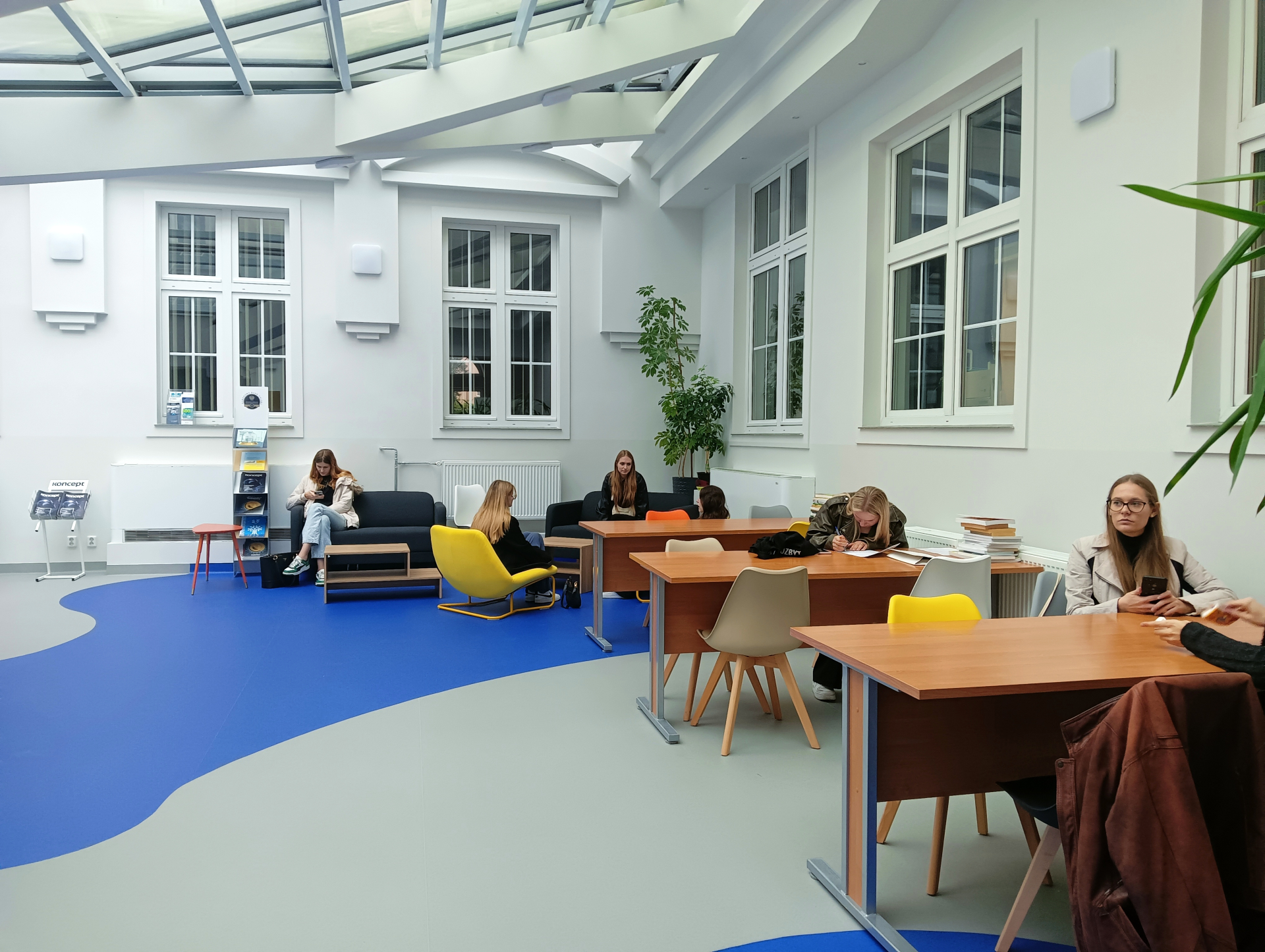 strefa relaksu na Wydziale Nauk Ekonomicznych, grupa studentów z książkami i telefonami w rękach