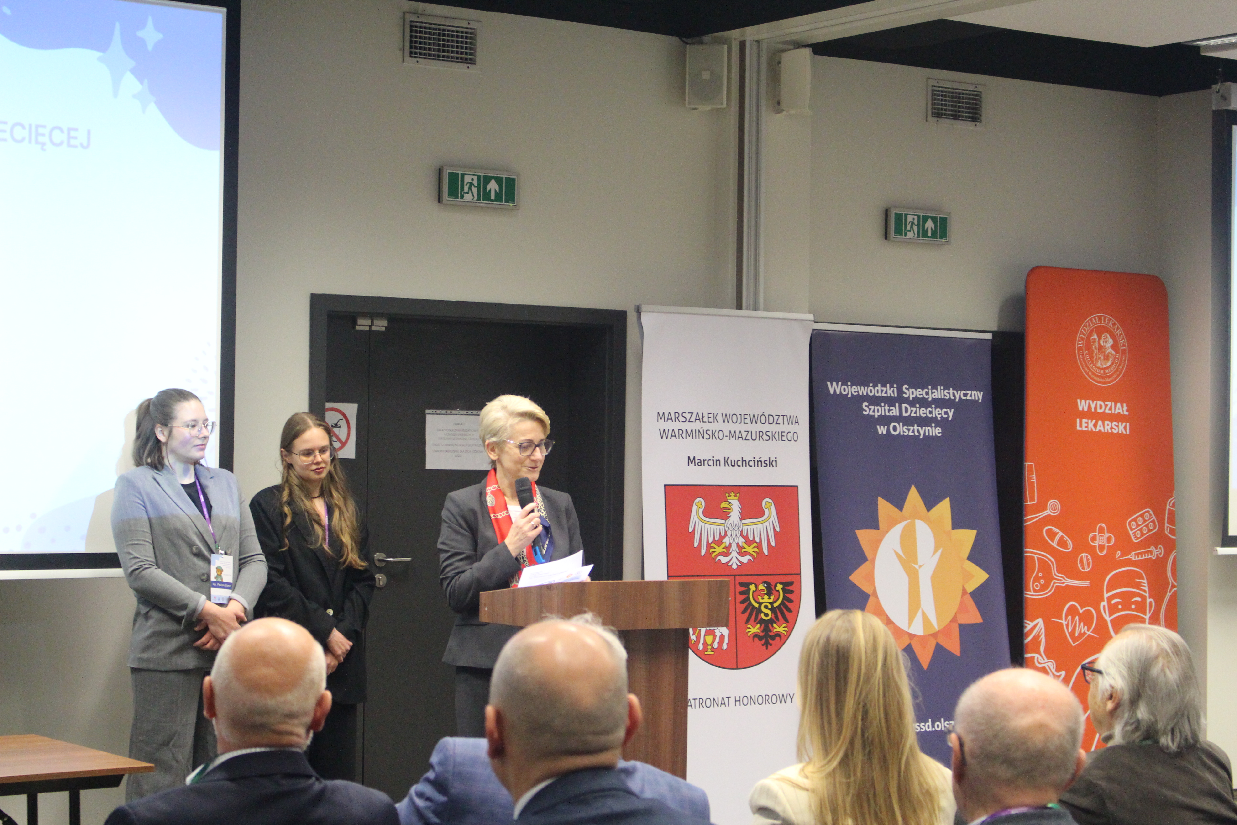 Trzy kobiety stoją przed publicznością