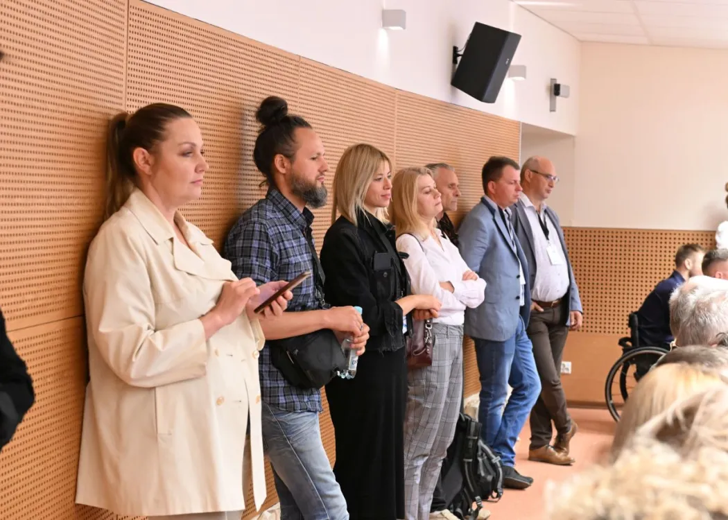 uczestnicy konferencji stoją pod ściana