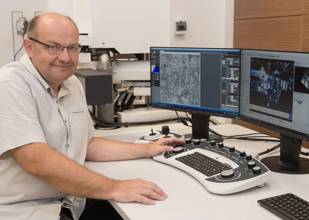 prof. Lewczuk siedzi przed mikroskopem elektronowym