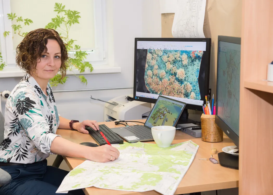 Renata Pelc-Mieczkowska siedzi przy biurku i czyta mapy 