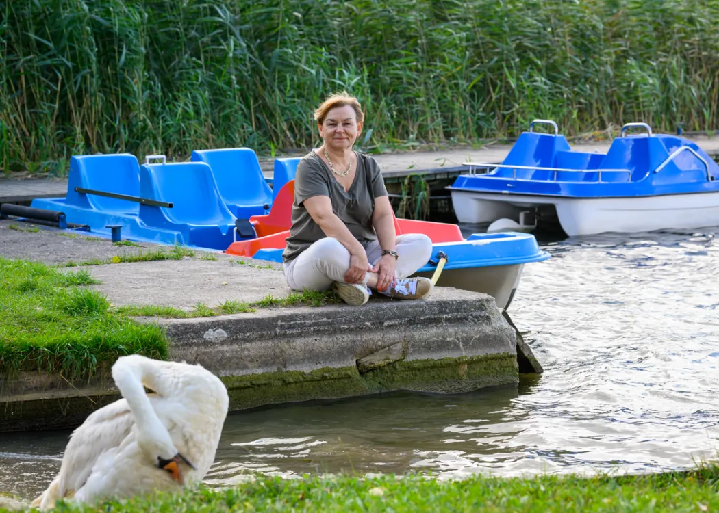 Grażyna Furgała-Selezniow siedzi na przystani kortowskiej nad jeziorem