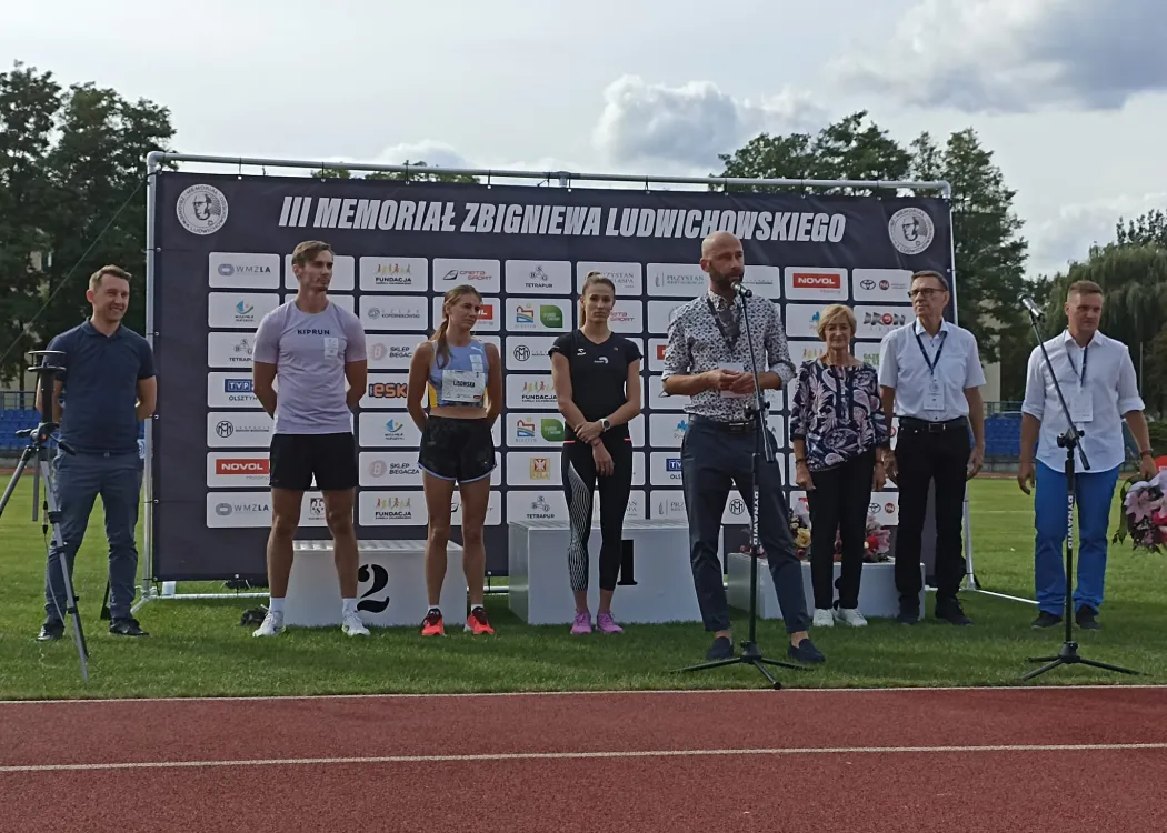 Sławomir Przybyliński stoi ze sportowcami i Piotrem Grzymowiczem 