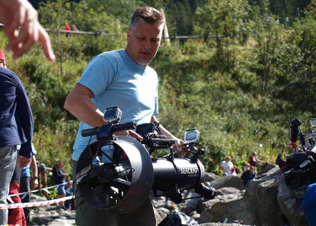 dr Piotr Dynowski niesie skuter podwodny