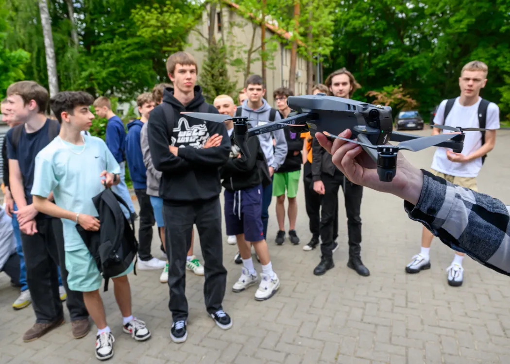 studenci stoją i oglądają pokaz drona