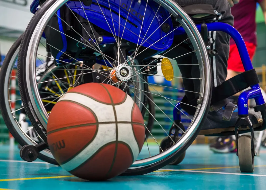 Zdjęcie przedstawia piłkę leżąca przy wózku sportowca z niepełnosprawnością