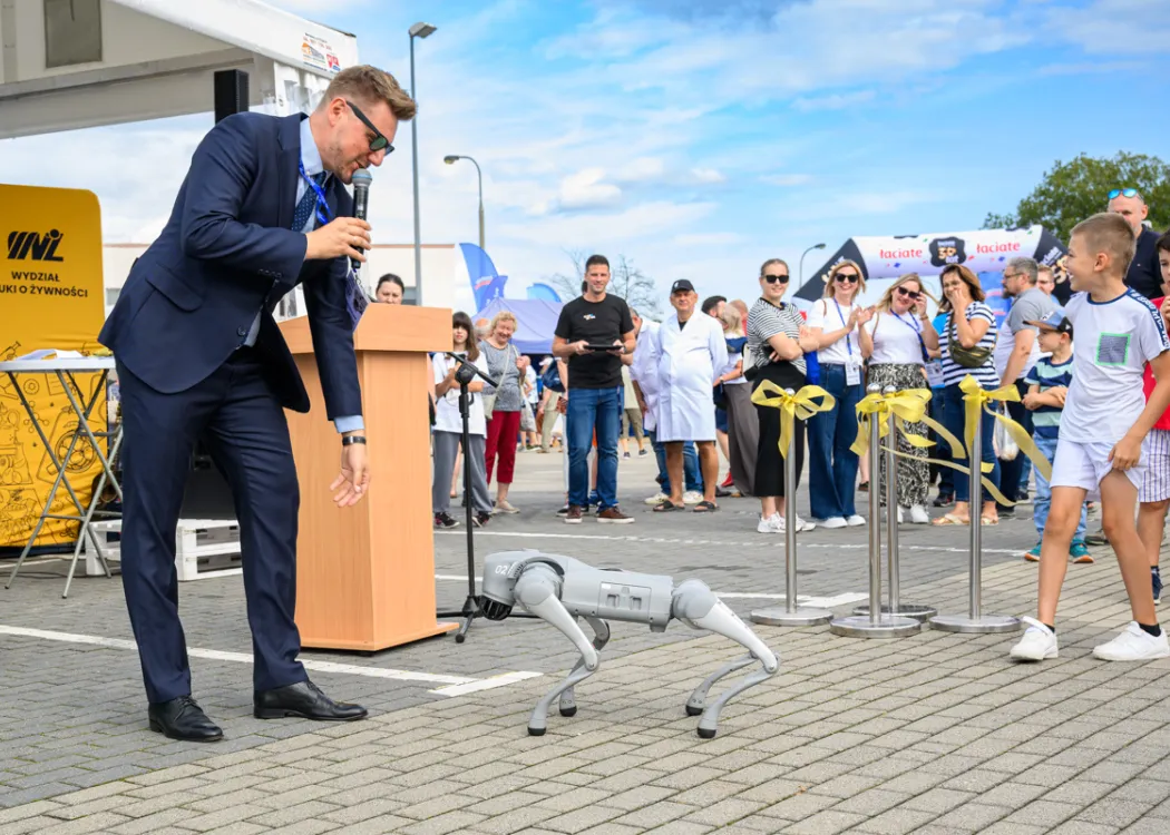 Święto Sera 2025: mężczyzna pochyla się nad robotem-psem, w tle uczestnicy wydaarzenia