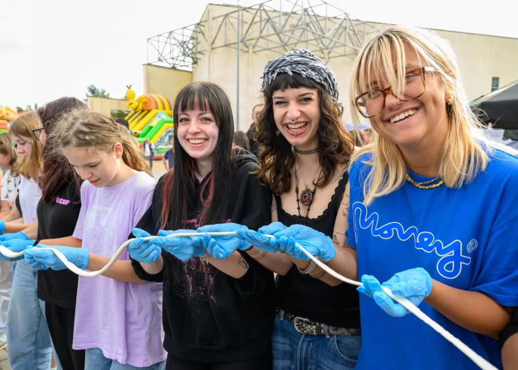 Święto Sera w Olsztynie. Na zdjęciu znajduje się kilka uśmiechniętych dziewczyn trzymających rozciągnięty ser mozzarella
