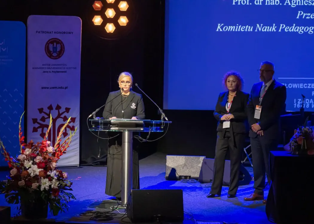 Zjazd pedagogiczny: przemawia jedna z prelegentek, w czarnej sukni