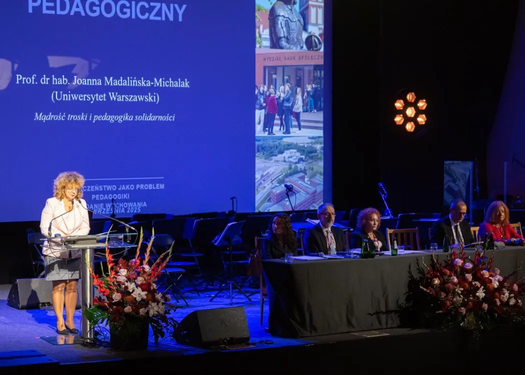 Zjazd pedagogiczny: przemawia prelegentka na stojąco, obok widać siedzące osoby przy stole