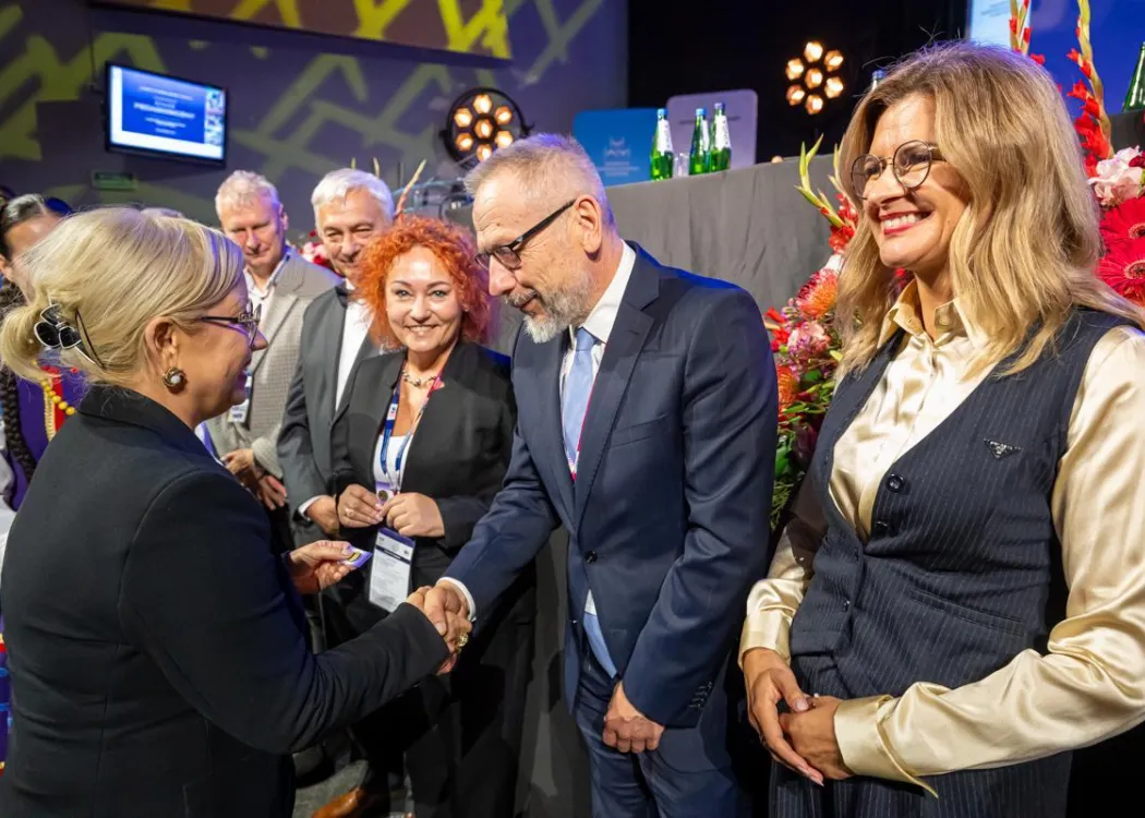 Zjazd pedagogiczny: kilka osób stoi przed sceną, uściski dłoni