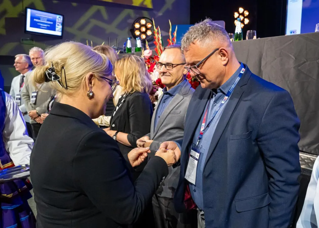 Zjazd pedagogiczny: kilka osób stoi przed sceną, uściski dłoni