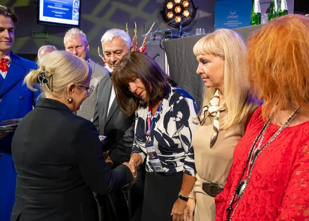 Zjazd pedagogiczny: uścisk dłoni kobiecie, w tle stoi kilka osób