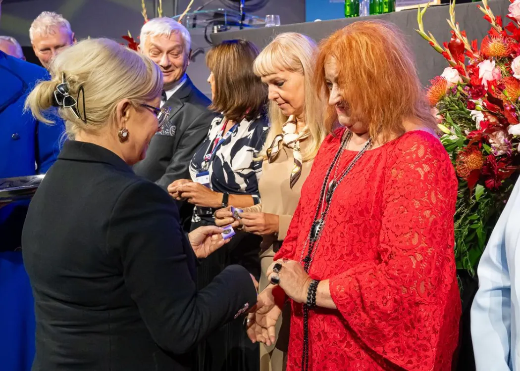 Zjazd pedagogiczny: uścisk dłoni kobiecie, w tle stoi kilka osób