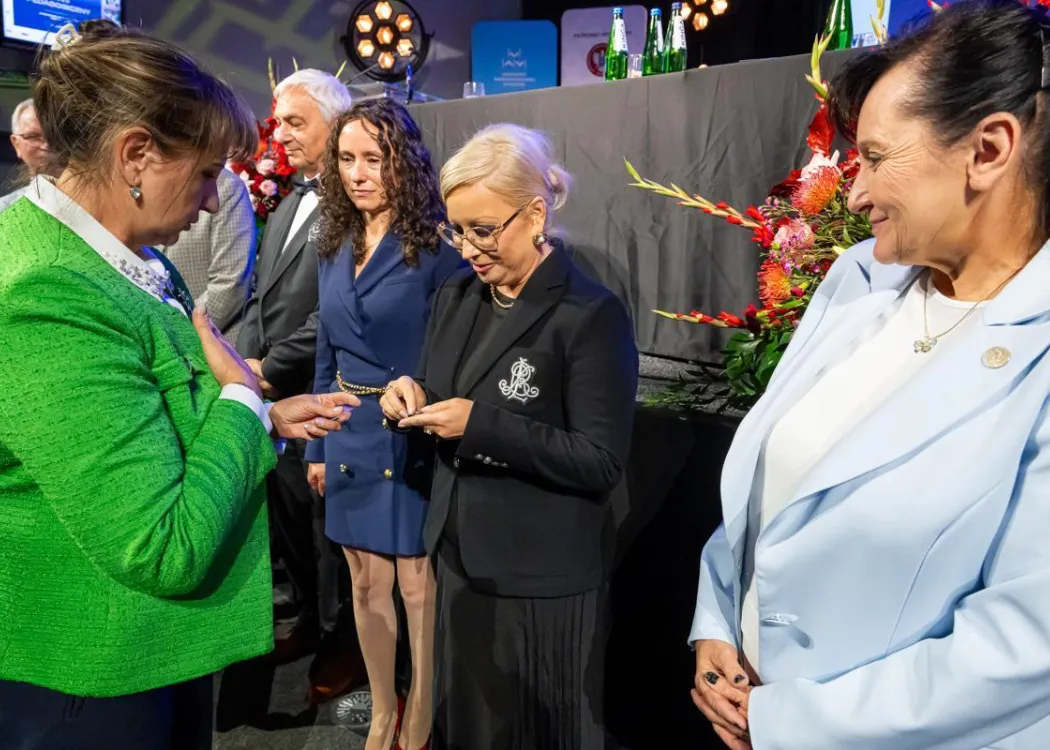 Zjazd pedagogiczny: uścisk dłoni kobiecie, w tle stoi kilka osób