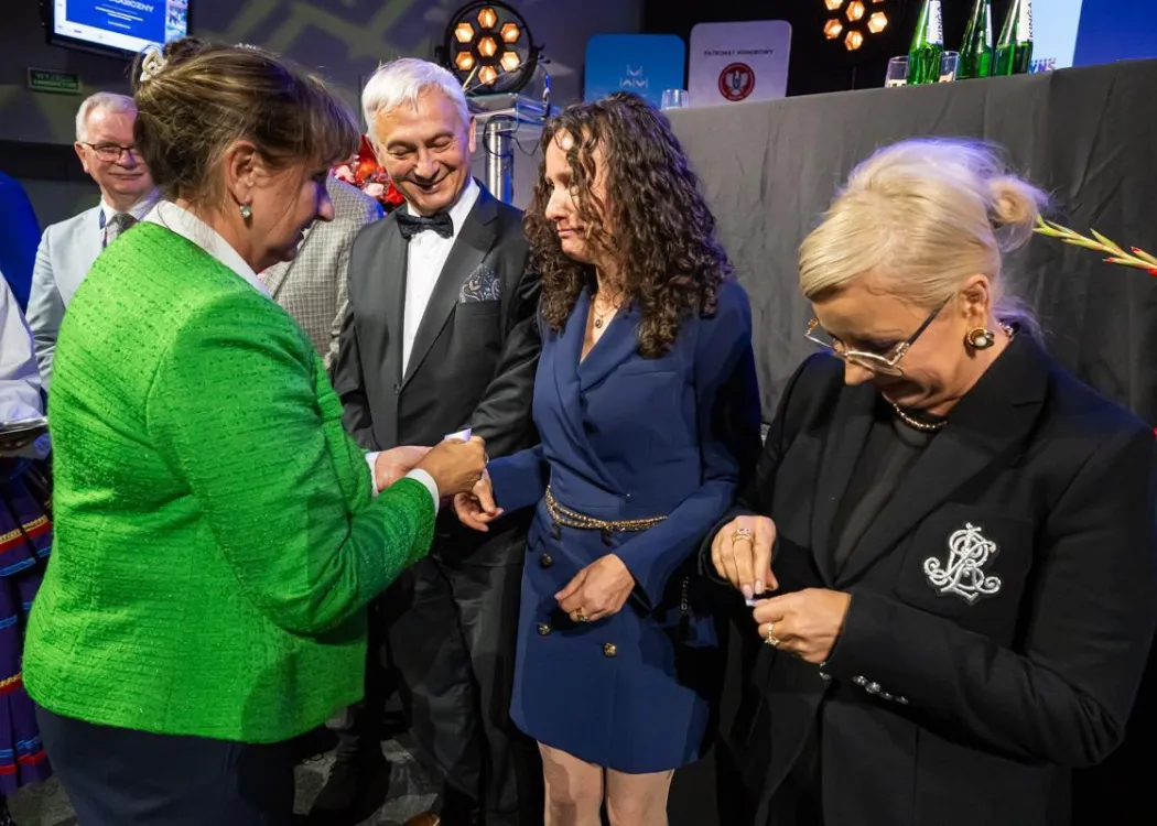 Zjazd pedagogiczny: uścisk dłoni kobiecie, w tle stoi kilka osób