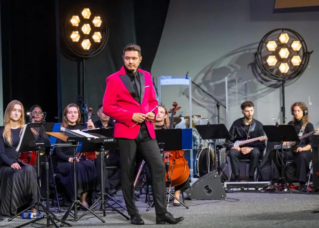 Zjazd pedagogiczny: na scenie orkiestra muzyczna z dyrygentem 