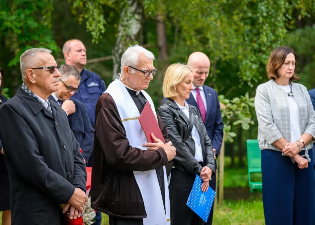 zgromadzeni stoją i słuchają, na pierwszym planie ksiądz