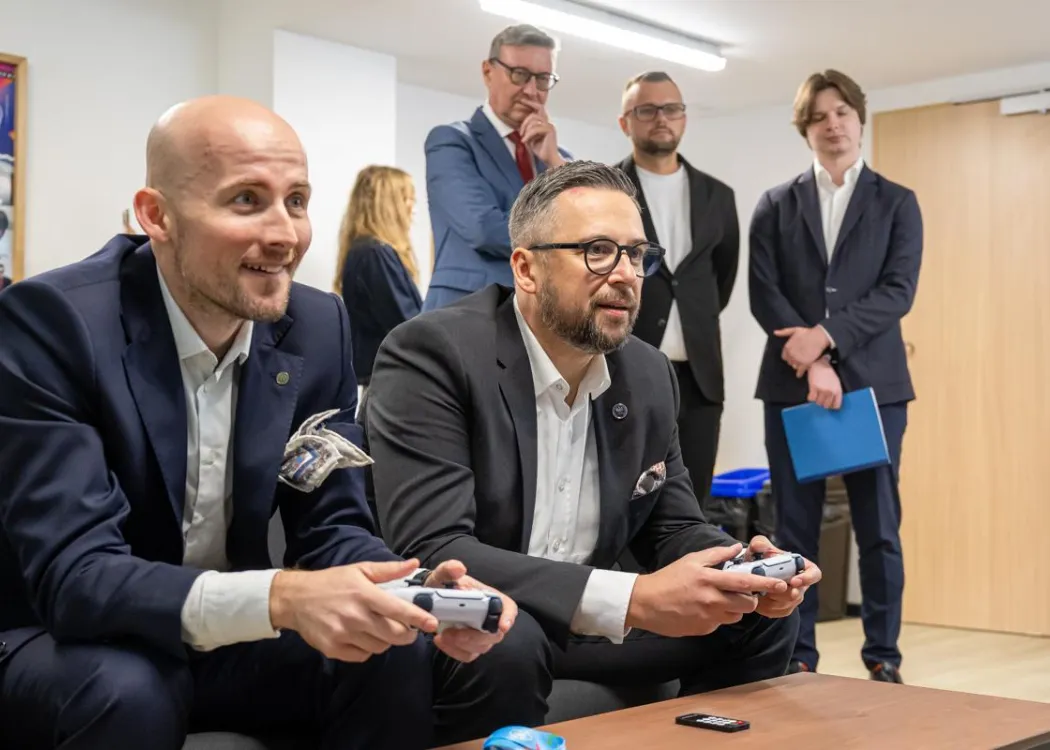 Otwarcie Domu Studenckiego nr 10: Bogusław Stec i Marcin Kulasek grają na konsoli, w tle inne osoby