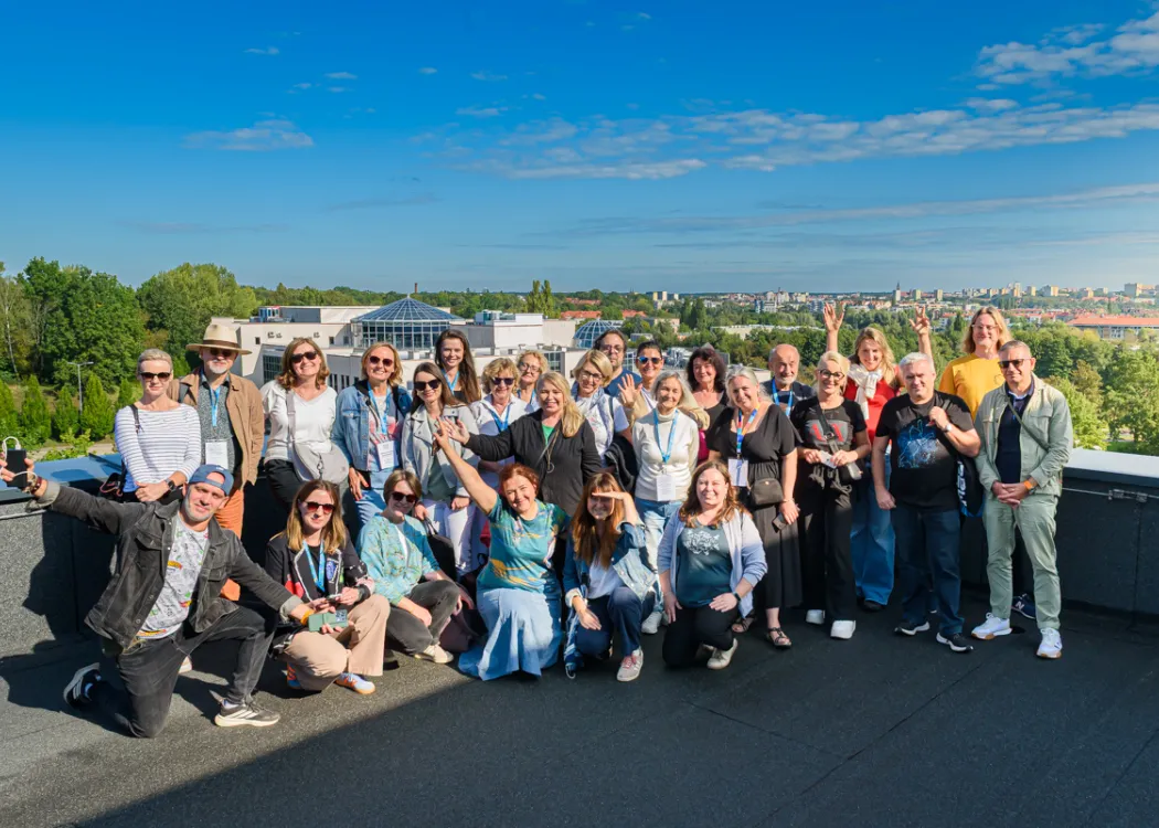 XXXII Konferencja Redaktorów Czasopism Akademickich i Portali Uczelnianych w Olsztynie - zdjęcie grupowe uczestników na dachu Kortosfery, w tle panorama Olsztyna