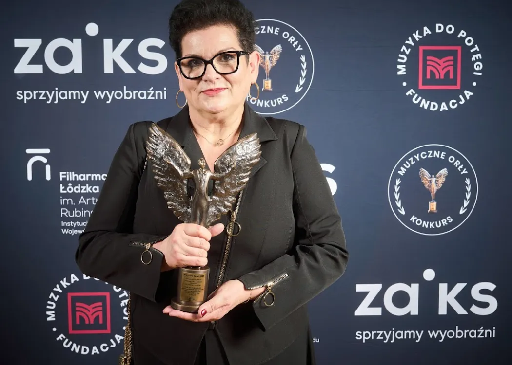 Prof. Ilona Dulisz w czarnym kostiumie trzyma statuetkę 