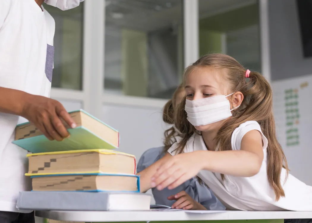 Dziewczynka w maseczce sięga po książki 