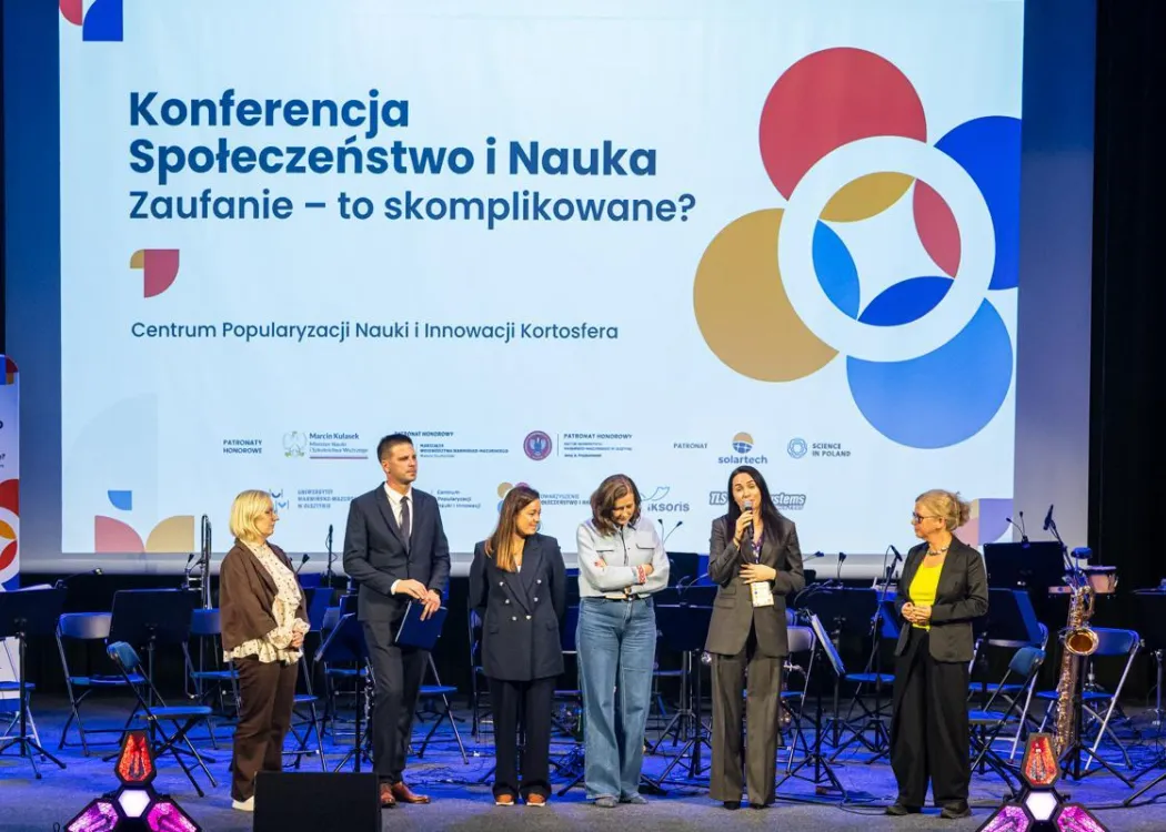 Konferencja SPIN: organizatorzy stoją na scenie. Do mikrofonu wypowiada się Iwona Kieda