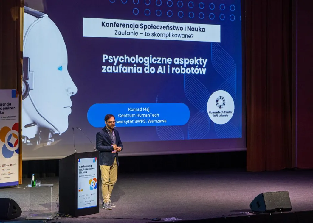 Konferencja SPIN: Konrad Maj przemawia, w tle ekran z napisem Psychologiczne aspekty zaufania do AI i robotów