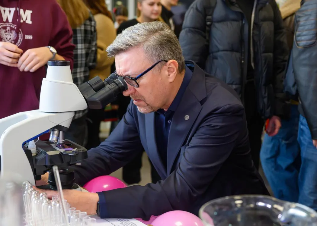 Student EXPO 2025: rektor UWM prof. Jerzy Przyborowski patrzy przez mikroskop 