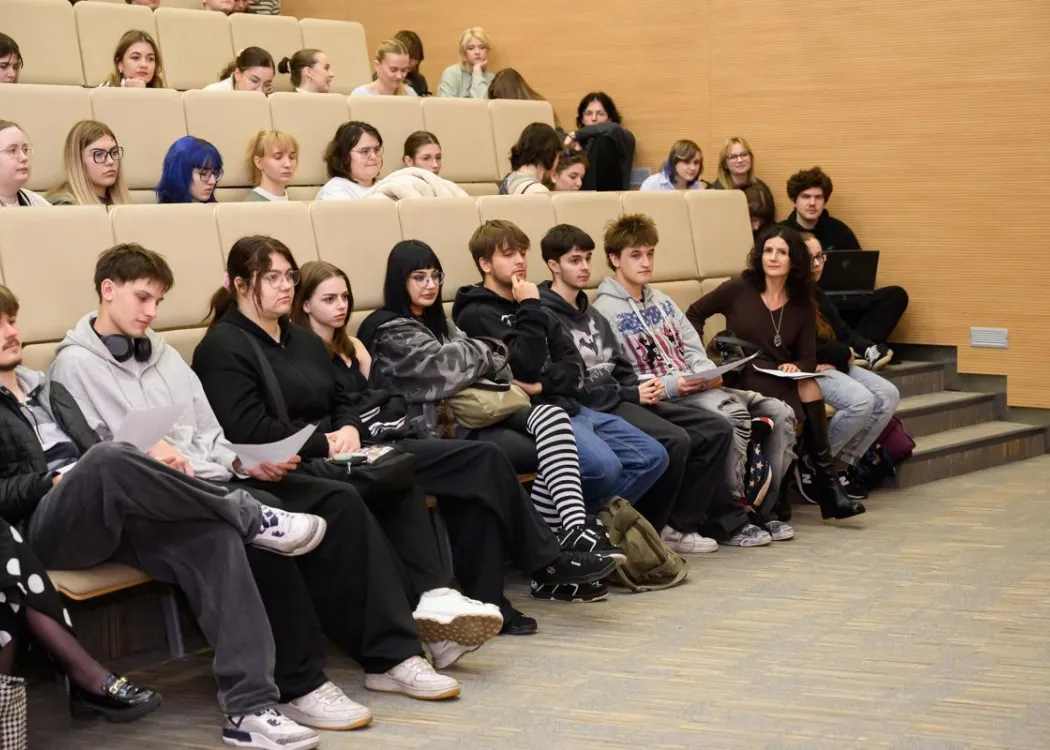 Studenci siedzą w Auli Teatralnej na spotkaniu z absolwentem 