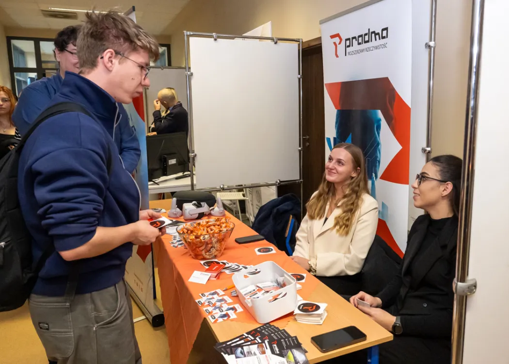 student stoi naprzeciwko stoiska i zbiera informacje o firmie