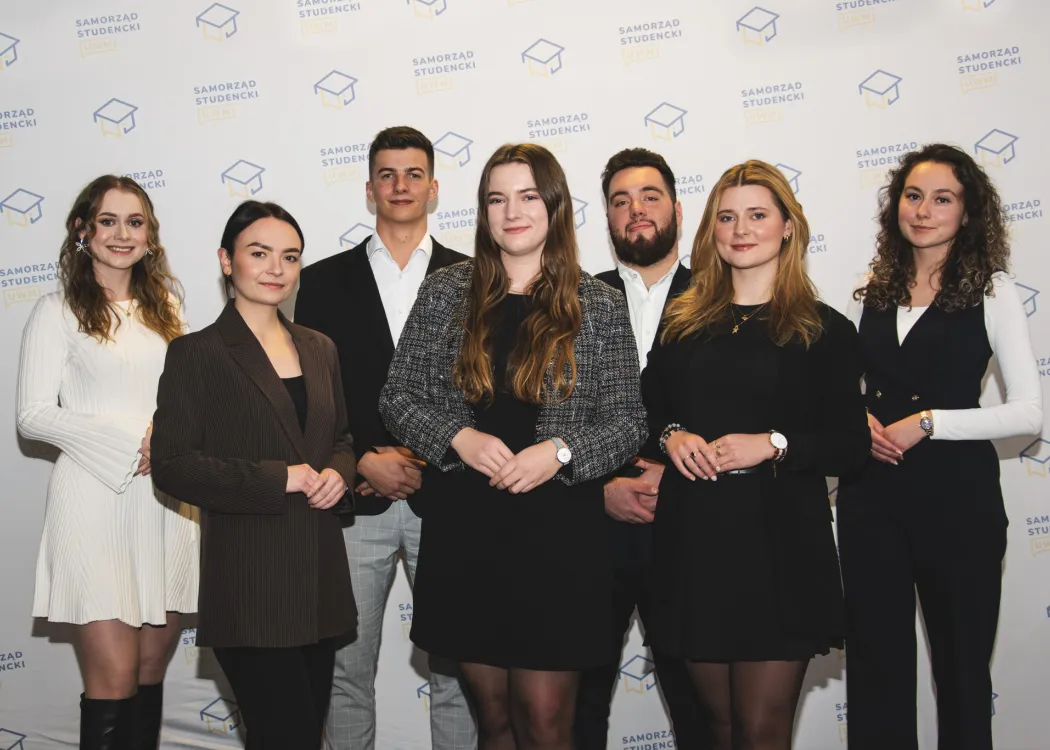 Rada Uczelniana Samorządu Studenckiego - skład prezydium. Siedem osób stoi na tle ścianki z logo RUSS / fot. Archiwum RUSS UWM