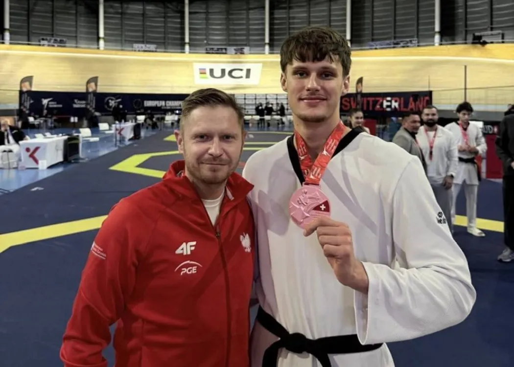 Szymon Piątkowski (po prawej) z medalem na szyi. Obok stoi jego trener