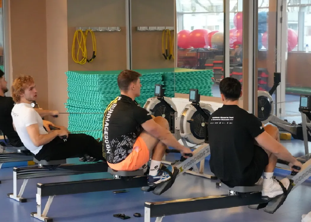mężczyźni ćwiczący na ergometrach wioślarskich 