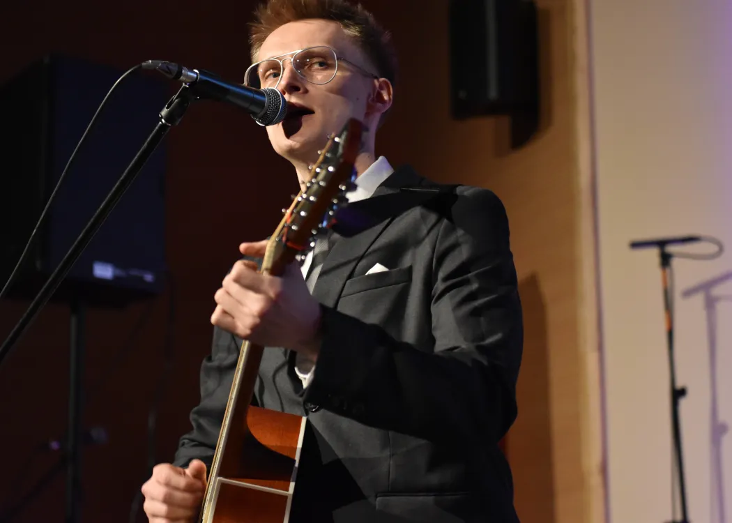 Dyplomatorium Wydziału Sztuki 2025: student gra na gitarze i śpiewa