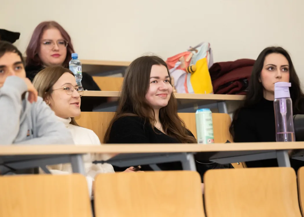 studenci siedzą w ławkach i słuchają wykładu