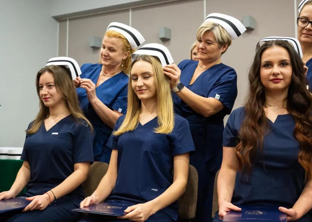 Dyplomatorium SZP: pielęgniarki przypinają dziewczynom czepki