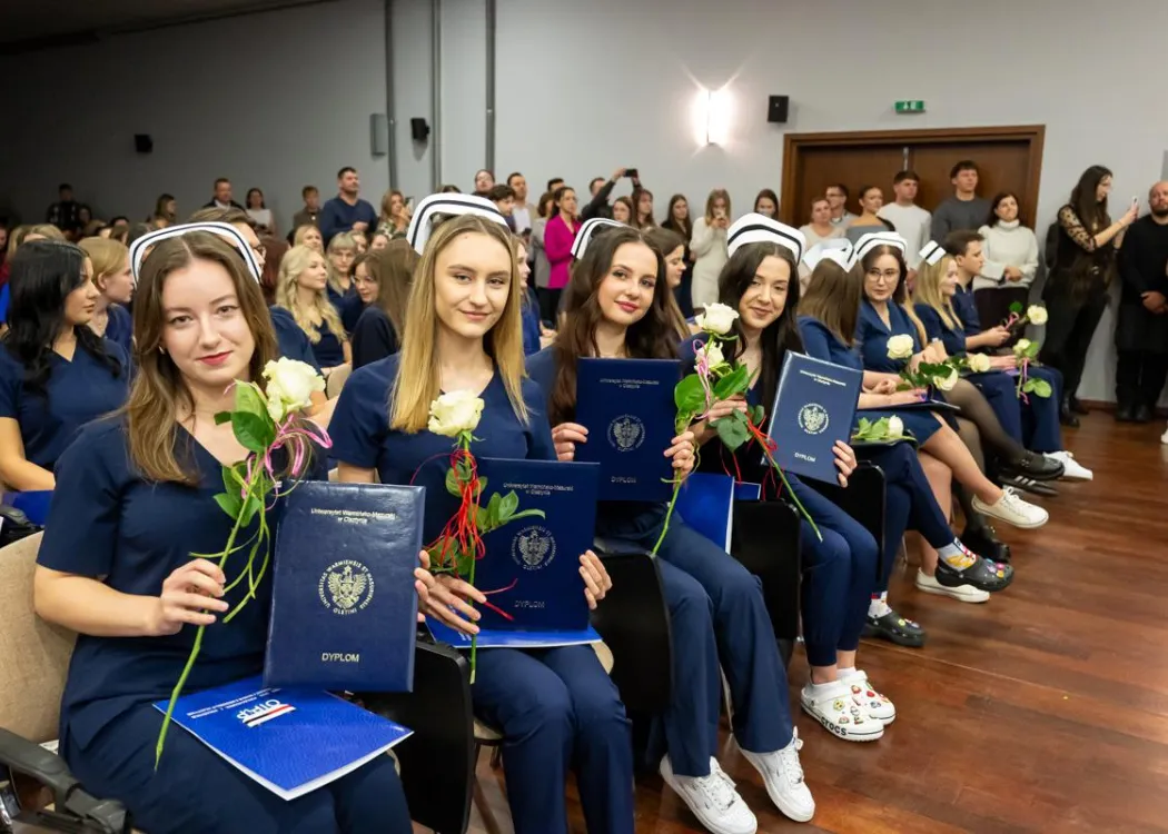 Dyplomatorium SZP: siedzą absolwenci w czepkach z dyplomami 