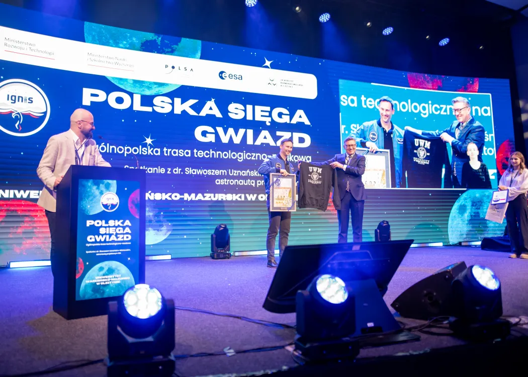 Spotkanie ze Sławoszem Uznańskim-Wiśniewskim na UWM: Sławosz Uznański-Wiśniewski odbiera upominek od rektora