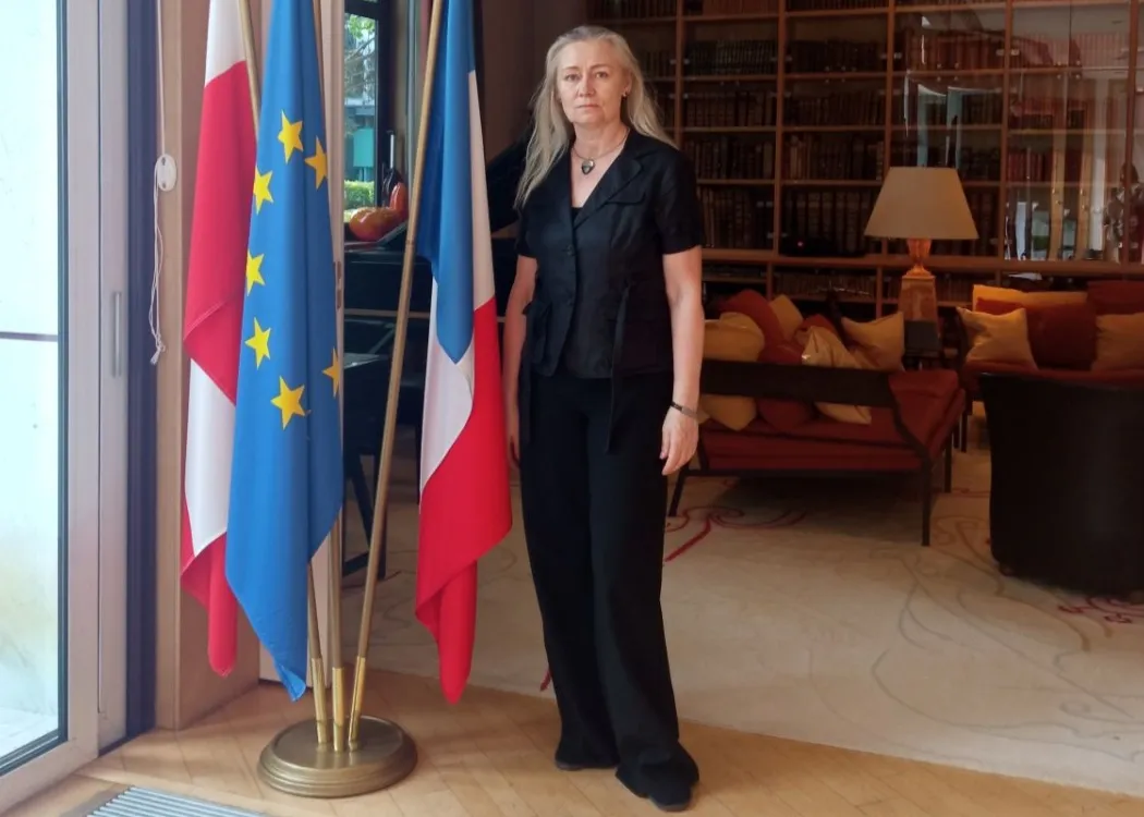 Prof. Iwona Anna Ndiaye stoi przy flagach w Ambasadzie Francuskiej